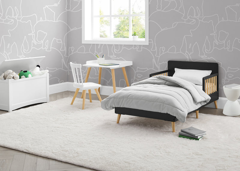 Children's bedroom with a bed, table, and chair against a gray wall with white line art. 7-Logan Wood Toddler Bed