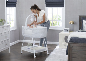Close-up of the baby bassinet showing the patterned fabric, canopy, and star-shaped toys hanging from the arch.
