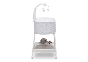 Front view of the baby bassinet with canopy, star and moon toys, and plush teddy bear inside, on a white frame.